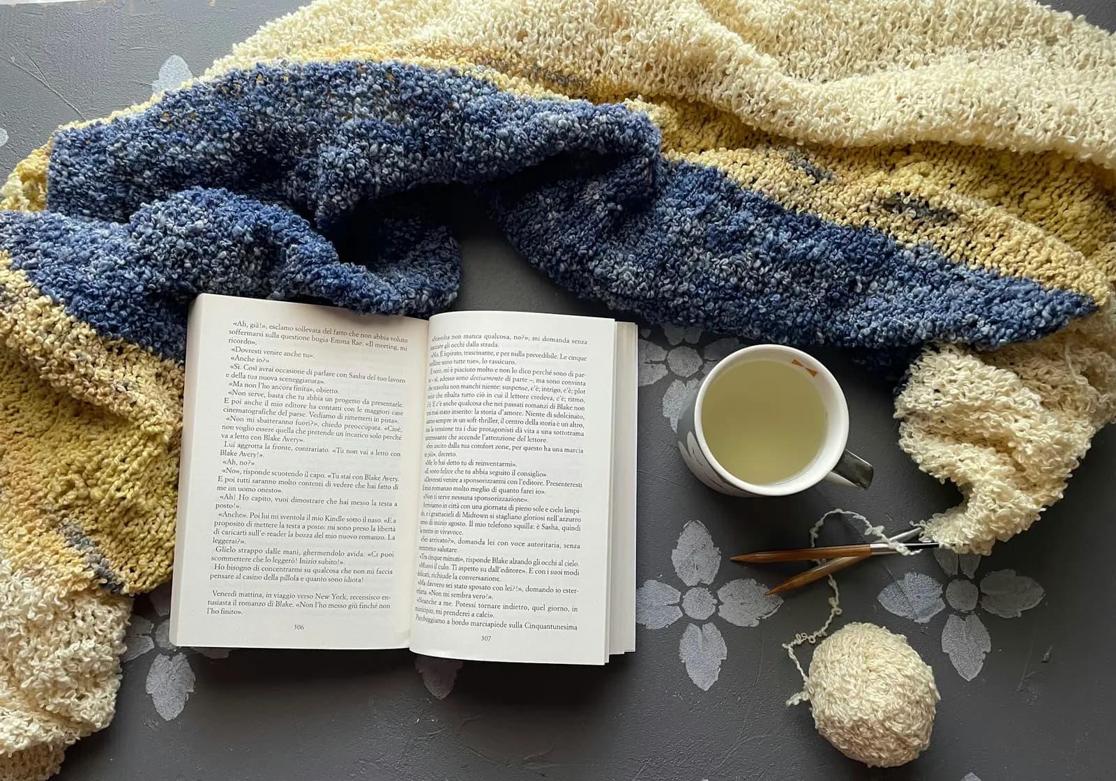 Livre ouvert et tasse de thé sur une couverture en laine
