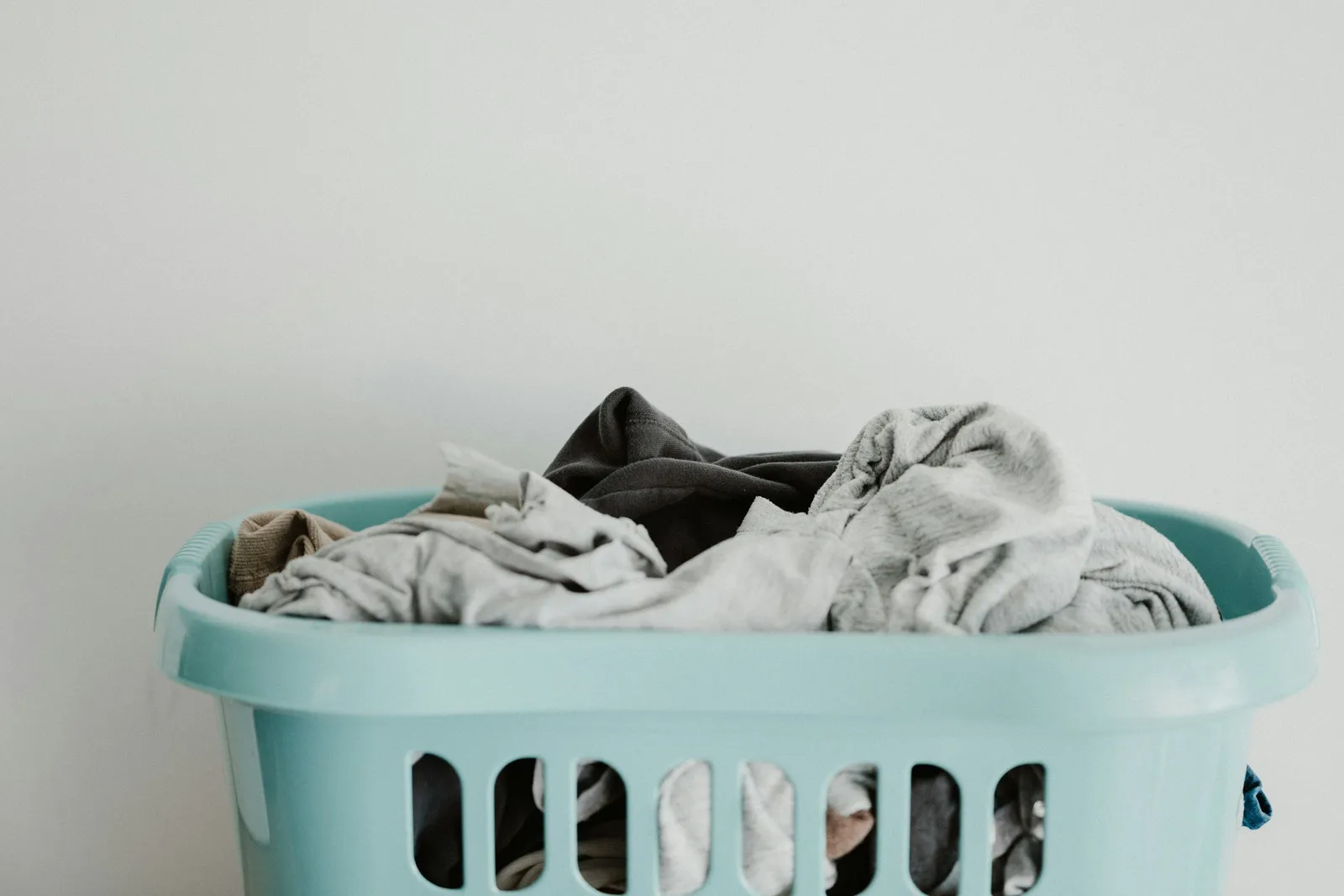 Panier à linge rempli de vêtements contre un mur blanc