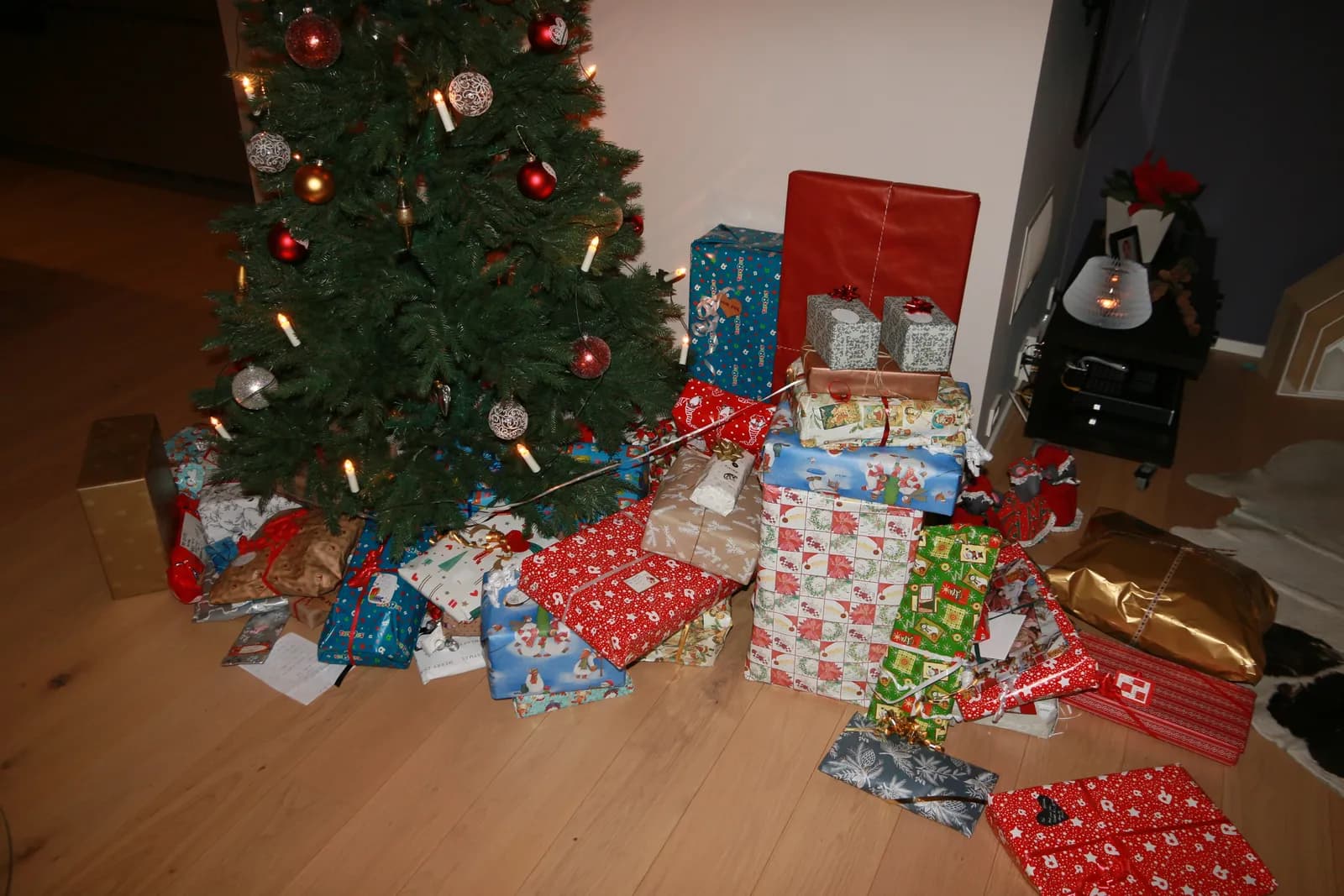 Paquets cadeaux emballés de papier rouge, bleu et doré au pied d'un sapin de Noël décoré