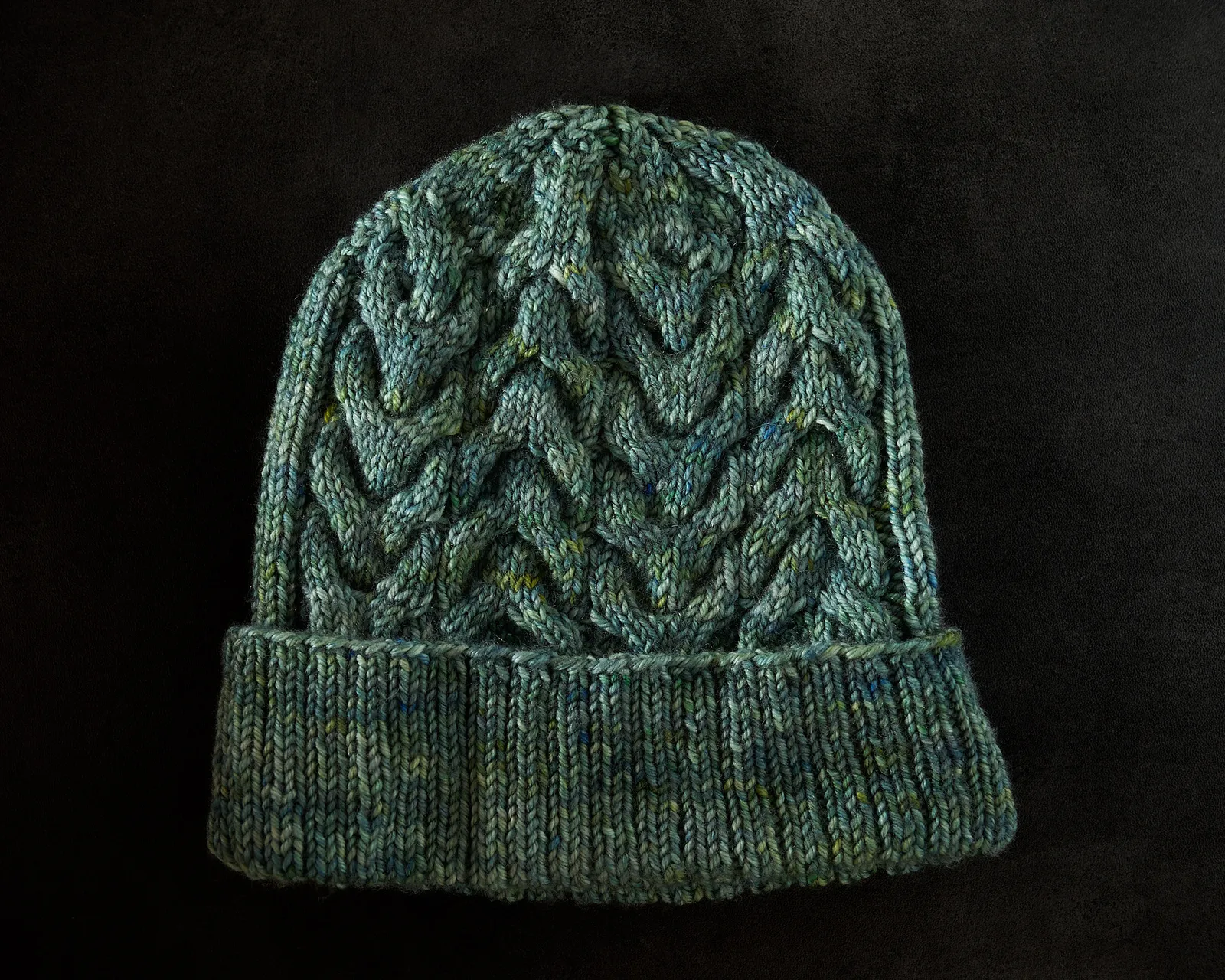Bonnet tricoté à la main en laine verte, avec un motif de torsades en relief